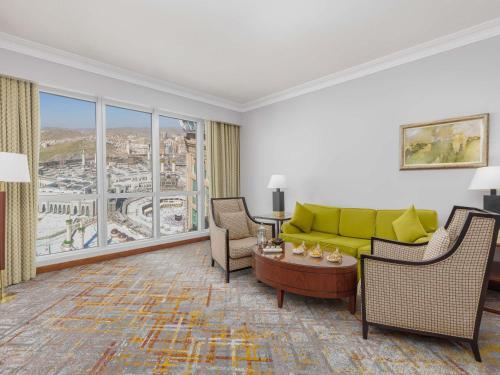 a living room with a couch and chairs and a large window at Swissotel Al Maqam Makkah in Makkah