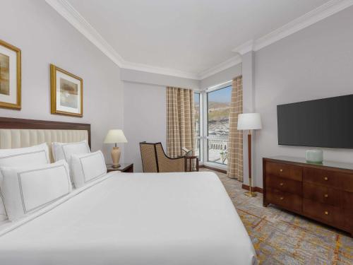 a bedroom with a large bed and a flat screen tv at Swissotel Al Maqam Makkah in Makkah