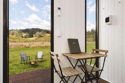 a table and chairs on a porch with a window at Haven Magnificence by Tiny Away in Conondale