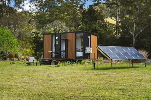 a tiny house with a solar panel in a field at Haven Magnificence by Tiny Away in Conondale