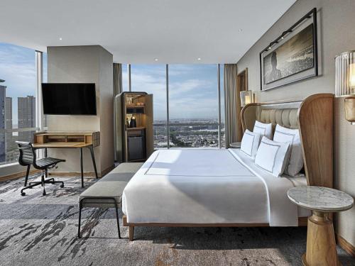 a hotel room with a large bed and a desk at Swissôtel Jakarta PIK Avenue in Jakarta