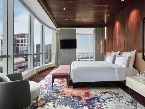 a bedroom with a large white bed and large windows at Swissôtel Jakarta PIK Avenue in Jakarta