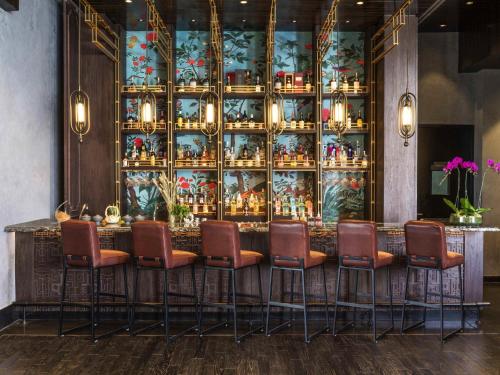 a bar in a restaurant with a wall of vases at Swissôtel Jakarta PIK Avenue in Jakarta