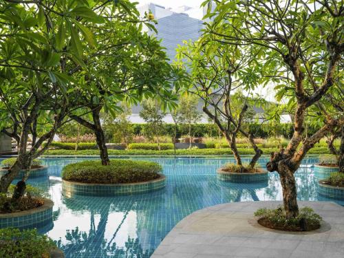 a swimming pool with trees in the middle of it at Swissôtel Jakarta PIK Avenue in Jakarta