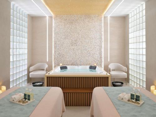 a spa room with a tub and two beds at Swissôtel Al Murooj Dubai in Dubai