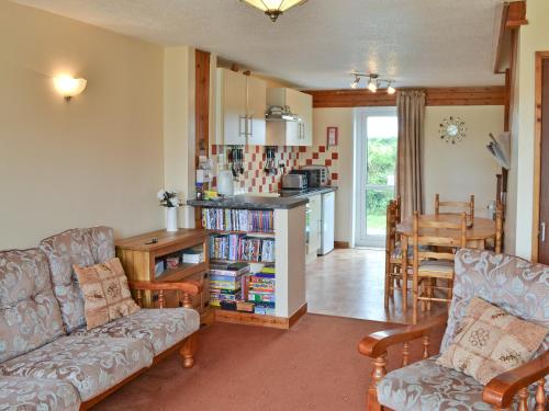 a living room with a couch and a table and a kitchen at Brambles in St. Agnes 