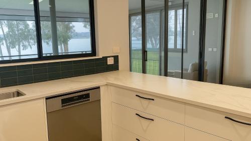 una cocina con armarios blancos y azulejos verdes en Wangi Waters, en Wangi Wangi