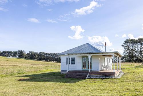 a small white tiny house in a field at Beltane Cottage in Canyonleigh
