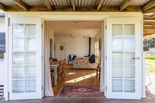 une porte ouverte sur un salon avec une table et des chaises dans l'établissement Beltane Cottage, à Canyonleigh