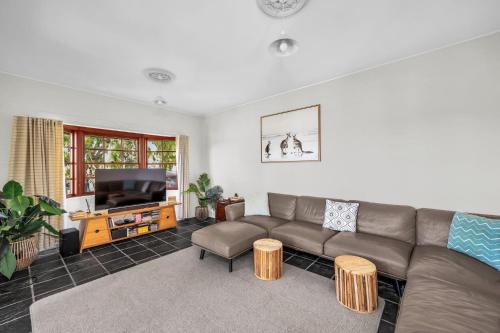 a living room with a couch and a flat screen tv at Cornwall Cottage in Merimbula
