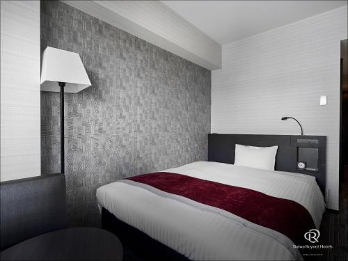 a bedroom with a large bed and a lamp at Daiwa Roynet Hotel Hiroshima-ekimae in Hiroshima