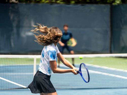 a woman holding a tennis racket on a tennis court at Fairmont El San Juan Hotel in San Juan