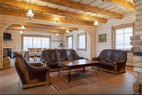 a living room with leather furniture and a table at Dabintos slėnis in Sumiliszki