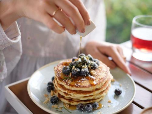 a person is eating a stack of pancakes with blueberries at Fairmont El San Juan Hotel in San Juan