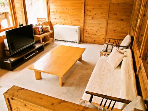 a living room with a couch and a table and a tv at ペンション木いちご PensionKiichigo in Zaō Onsen