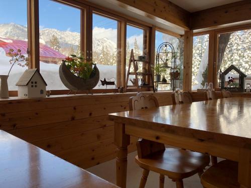 a dining room with a table and some windows at ペンション木いちご PensionKiichigo in Zaō Onsen
