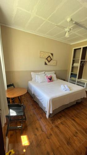 a bedroom with a white bed and a table at Pousada Monte Libano Petropolis in Nogueira