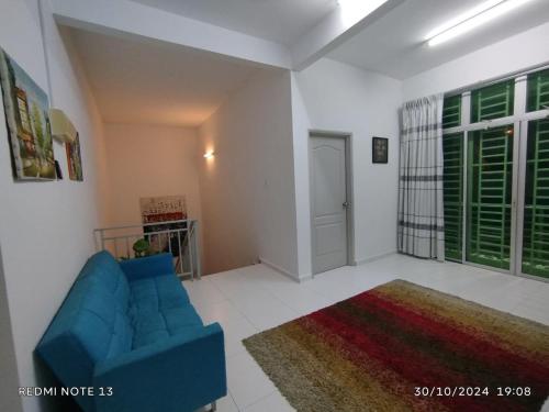 a living room with a blue couch and a rug at Tamu Homestay in Bemban