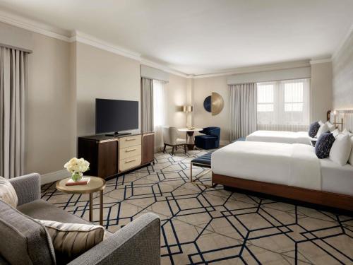 a large hotel room with a bed and a tv at Fairmont Hotel Macdonald in Edmonton