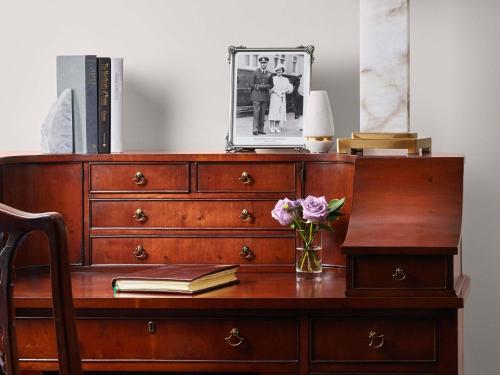 a wooden dresser with a vase of flowers and a book at Fairmont Hotel Macdonald in Edmonton