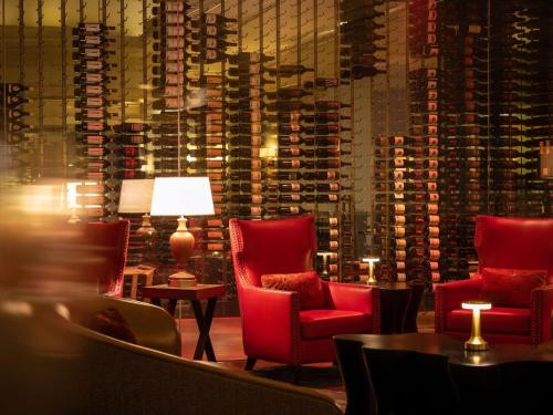 a room with red chairs and a wall of wine bottles at Fairmont Dallas in Dallas