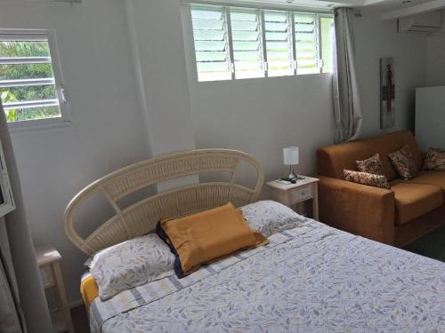 a bedroom with a bed and a couch and a window at Proprizen in Rivière-Salée
