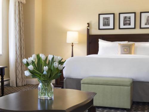 a hotel room with a bed and a vase of flowers on a table at Fairmont Le Manoir Richelieu in La Malbaie