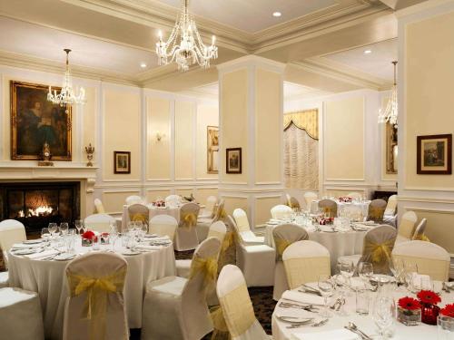 a banquet room with tables and chairs and a fireplace at Fairmont Le Manoir Richelieu in La Malbaie
