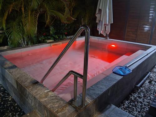 a hot tub with red water and a metal hand rail at Proprizen in Rivière-Salée