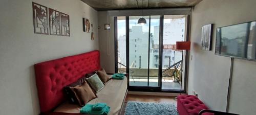 a living room with a red couch and a balcony at Temporarios Rosario en calle 9 de Julio y Oroño in Rosario