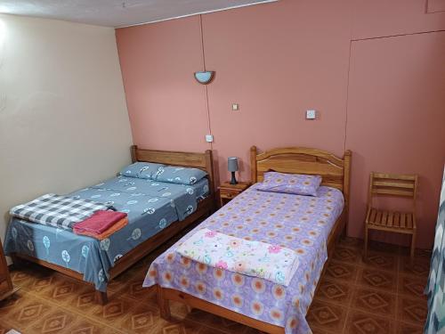 two beds in a small room with two chairs at Fleurvilla in Pereybere