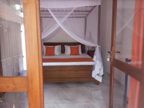 a bedroom with a canopy bed with orange pillows at Dishari Tangalle in Tangalle