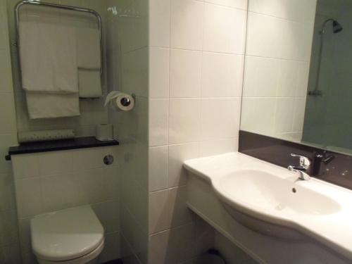 a bathroom with a sink and a toilet and a mirror at Lakeside International Hotel in Camberley