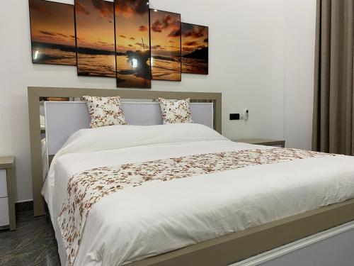 a bedroom with a white bed with four paintings on the wall at Hotel Magdalina Lagoon in Negombo