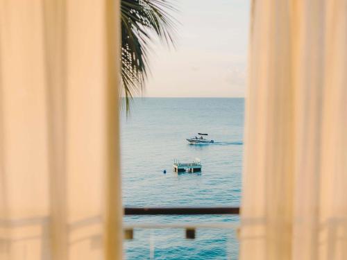 a view of a boat in the ocean from a window at Fairmont Royal Pavilion Barbados Resort in Saint James