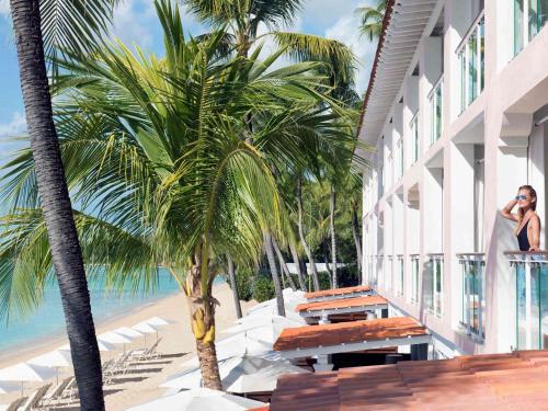 a woman talking on a cell phone next to a palm tree at Fairmont Royal Pavilion Barbados Resort in Saint James