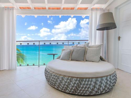 a room with a round ottoman in front of a window at Fairmont Royal Pavilion Barbados Resort in Saint James