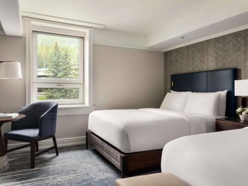 a hotel room with two beds and a desk and a window at Fairmont Banff Springs in Banff