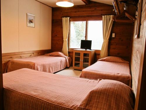 a room with three beds and a television in it at ペンション木いちご PensionKiichigo in Zaō Onsen