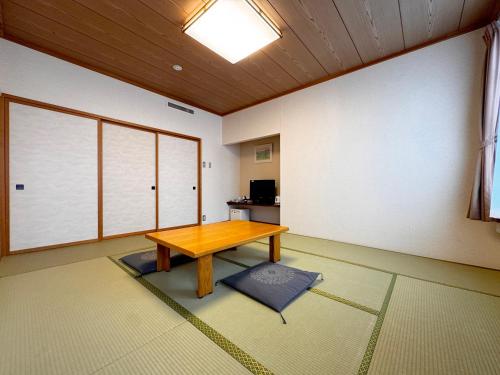 a room with a wooden table on a rug at Hotel Cerulean Alpine in Otari