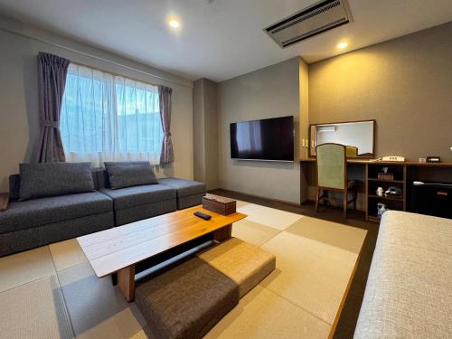 a living room with a couch and a flat screen tv at Hotel Cerulean Alpine in Otari