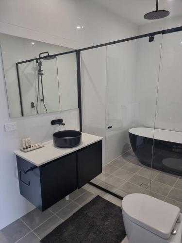 a bathroom with a sink and a tub and a toilet at Serenity Valley Haven Ellalong in Ellalong