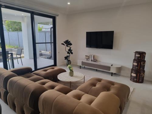 a living room with a large couch and a television at Serenity Valley Haven Ellalong in Ellalong
