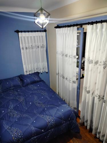 Schlafzimmer mit blauem Bett und weißen Vorhängen in der Unterkunft Céntrico, a una cuadra de la Plaza Isabel la Católica, linda zona in La Paz