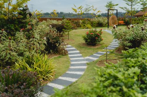 a walkway in a garden with flowers and plants at Monkeys Canopy Resort in Kajang