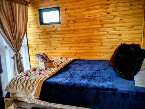 a bed in a room with a wooden wall at Cabaña Amanecer in Icononzo