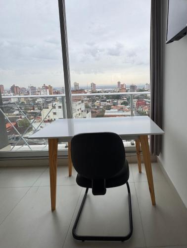 a white table and a black chair in front of a window at Central apartment in Asunción in Asuncion
