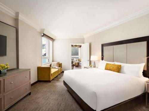 a bedroom with a large white bed and a living room at Fairmont Château Lake Louise in Lake Louise