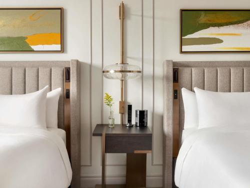 a bedroom with two beds and a table with a lamp at Fairmont Château Lake Louise in Lake Louise