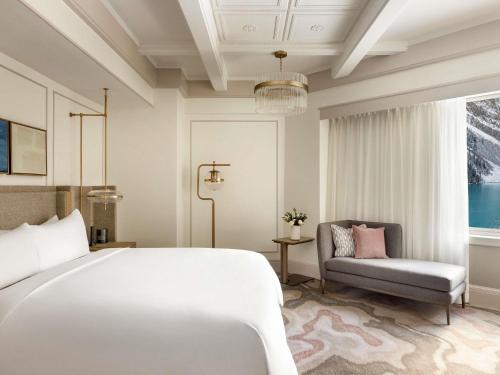 a bedroom with a large white bed and a chair at Fairmont Château Lake Louise in Lake Louise